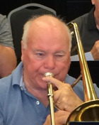 Len smiling holding a trombone